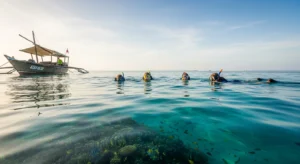 Zanzibar snorkeling tour on a traditional dhow boat near Mnemba Island with crystal-clear turquoise water, snorkelers entering the sea, and vibrant coral reefs visible beneath the surface in a calm tropical ocean setting.